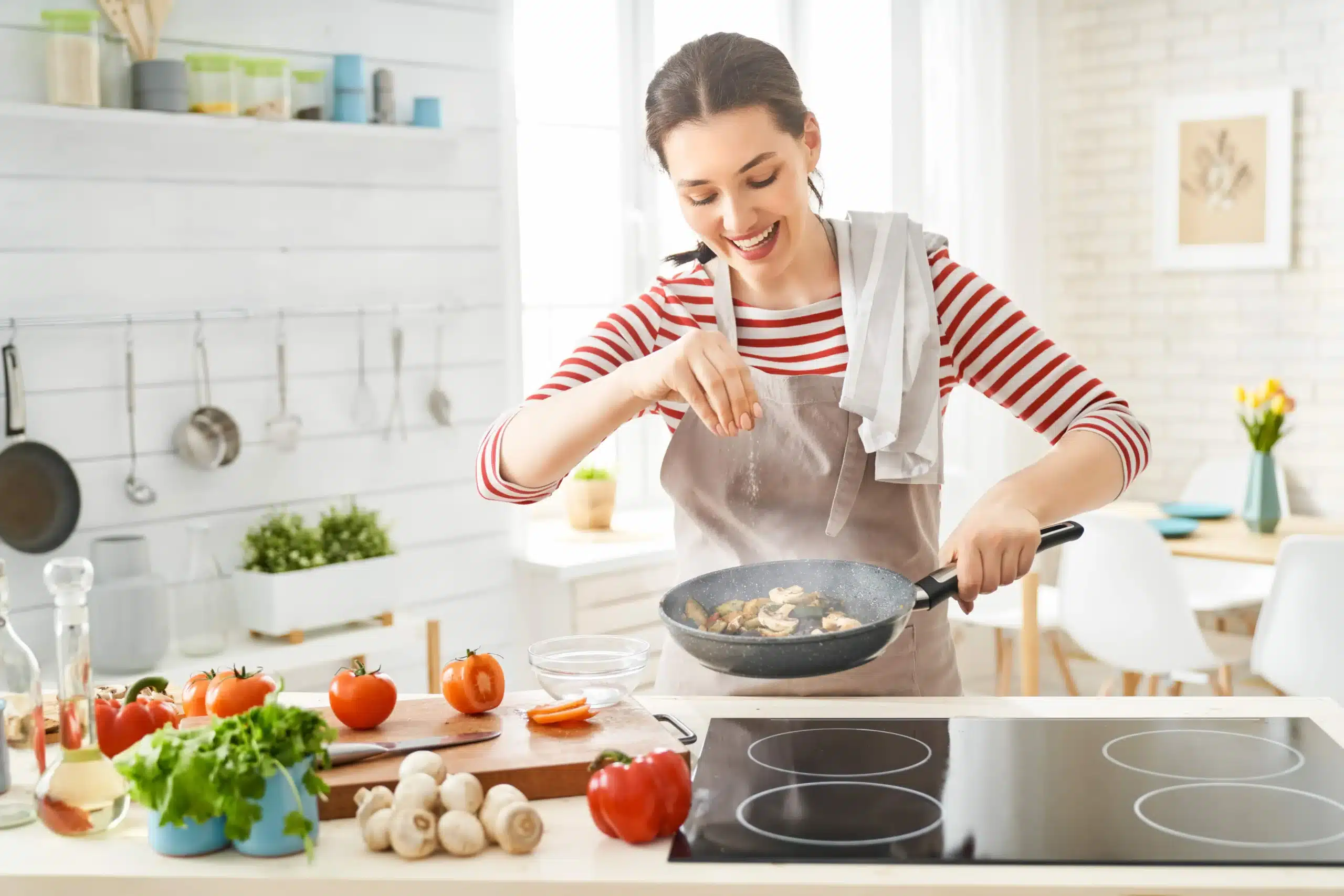 Amalia cooking with fresh vegetables on stove in bright kitchen