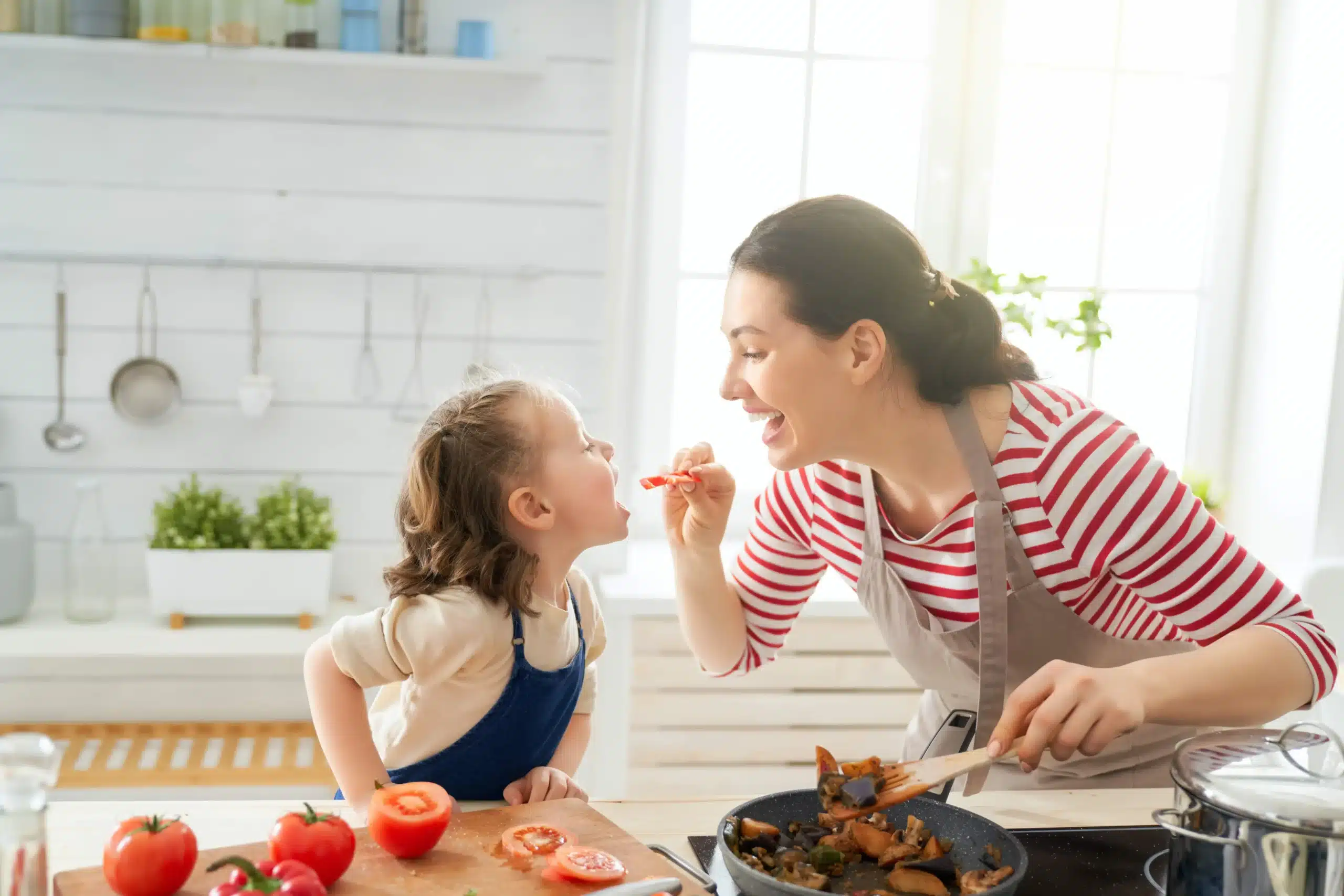 Amalia cooking with fresh vegetables and feeding daughter