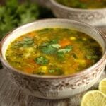 Lemon coriander soup with lime wedges and fresh herbs